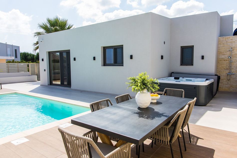 Bedroom with bed, sofa, accent wall, and modern lighting. Earth tones, neutral colors.
