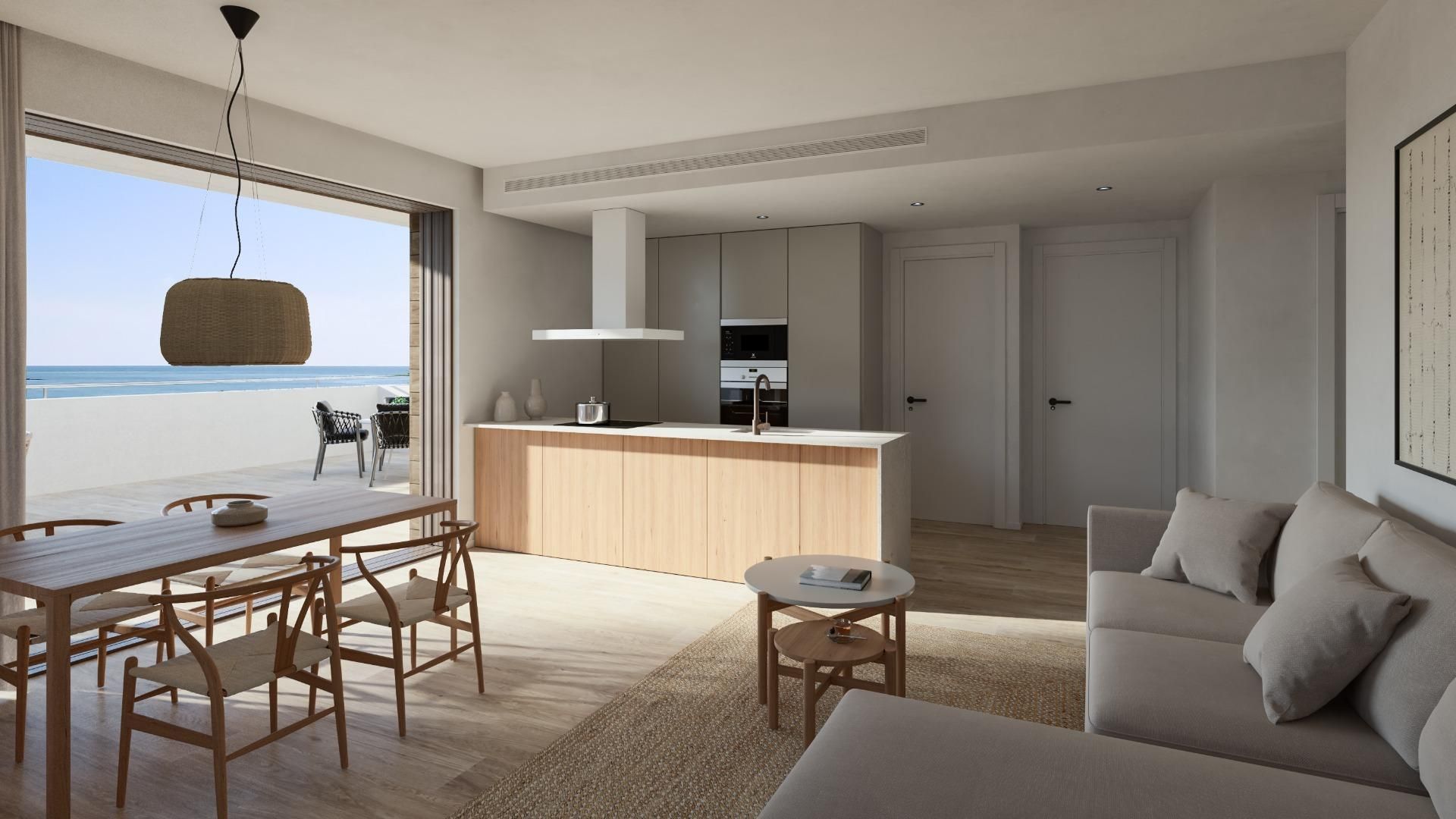 Espacio luminoso y diáfano con vistas a la playa. Cocina de madera clara, comedor y sofá beige.