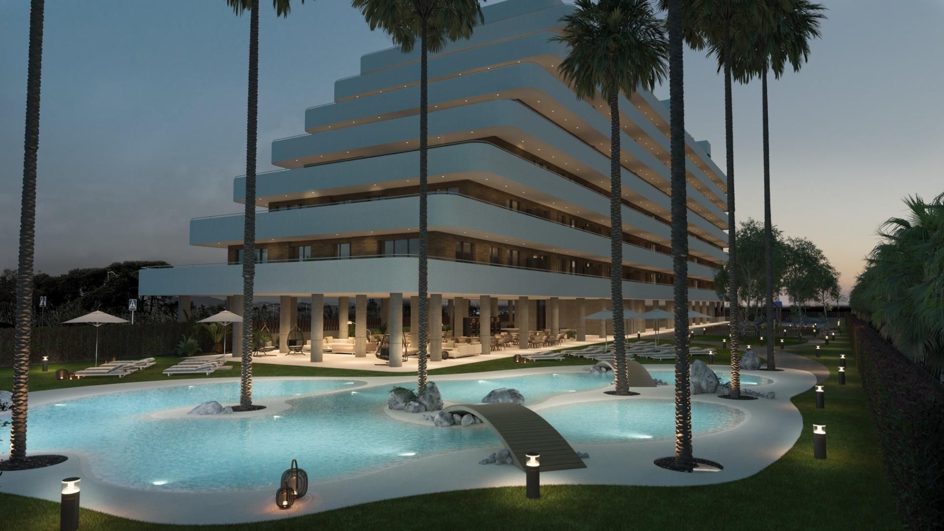 Un edificio blanco de varios niveles con piscina y palmeras al anochecer.