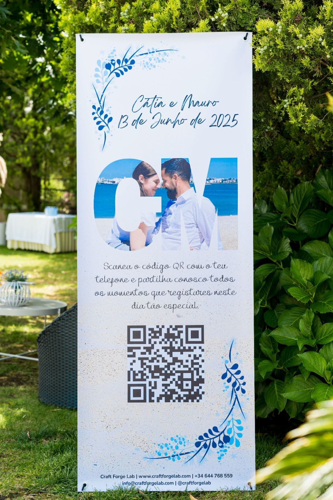 Pancarta de boda con foto de la pareja, texto y código QR, colocada al aire libre con detalles azules.