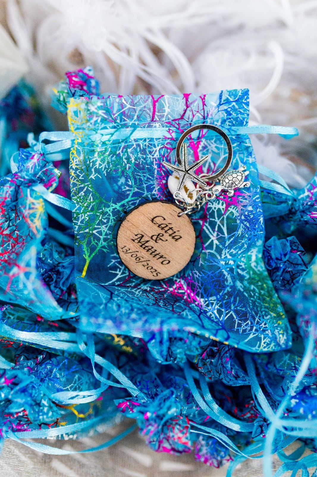 Bolsa de regalo azul estampada con llavero y etiqueta de corcho; nombres y fecha inscritos en la etiqueta.