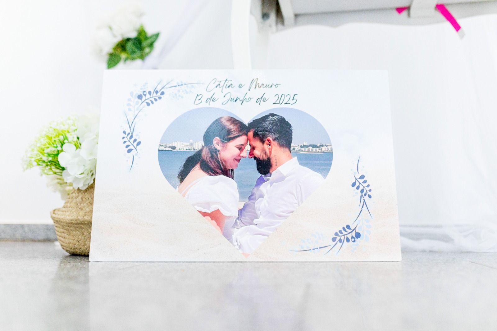 Letrero de madera con una foto de una pareja dentro de un corazón, detalles florales y fecha.