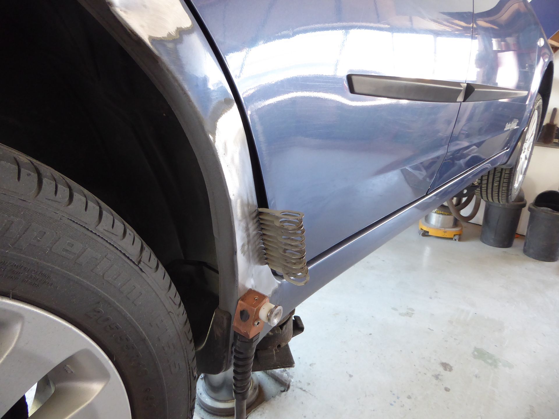 In einer Garage wird an einem blauen Auto gearbeitet