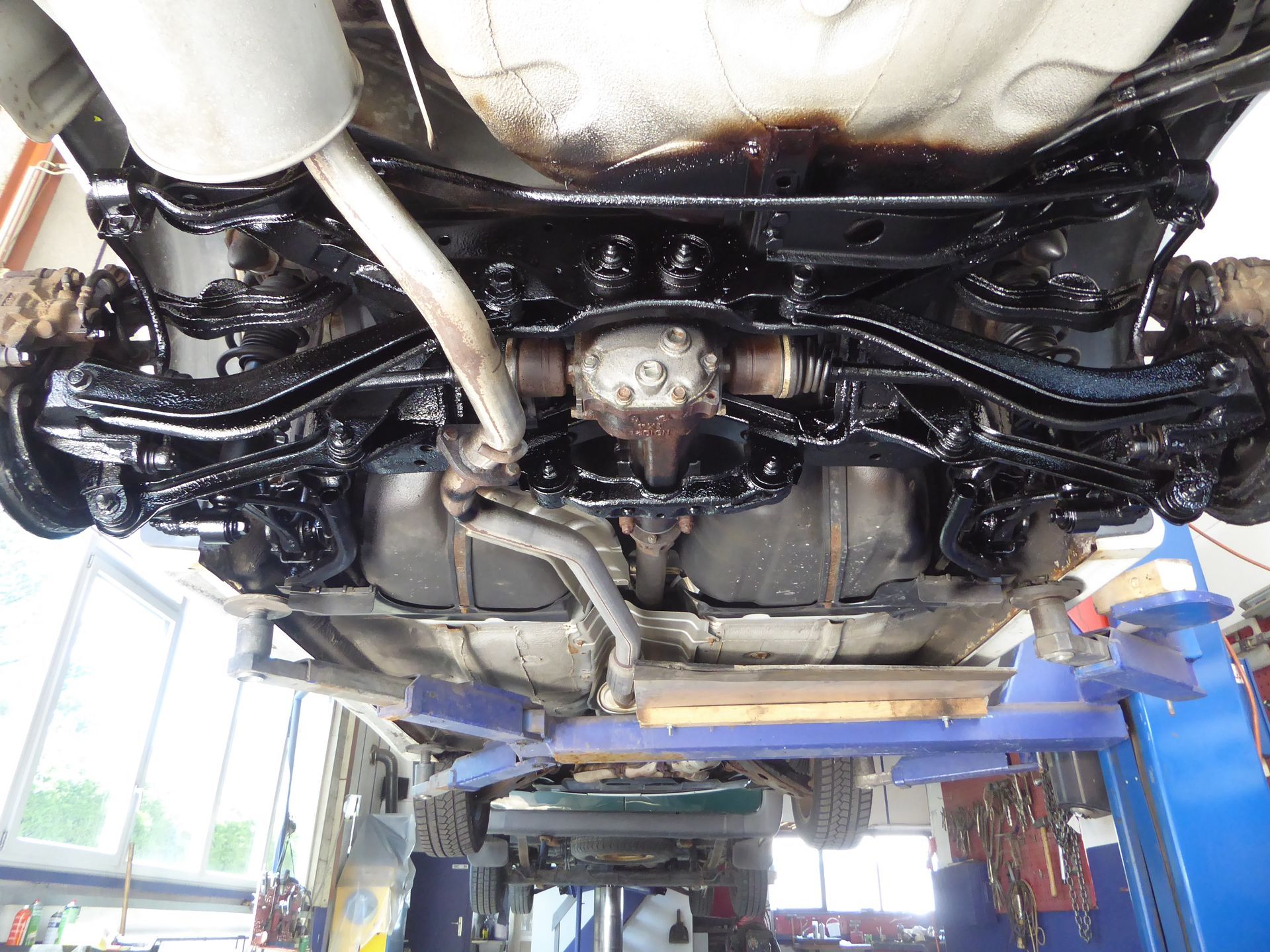 Die Unterseite eines Autos liegt auf einer Hebebühne in einer Garage.