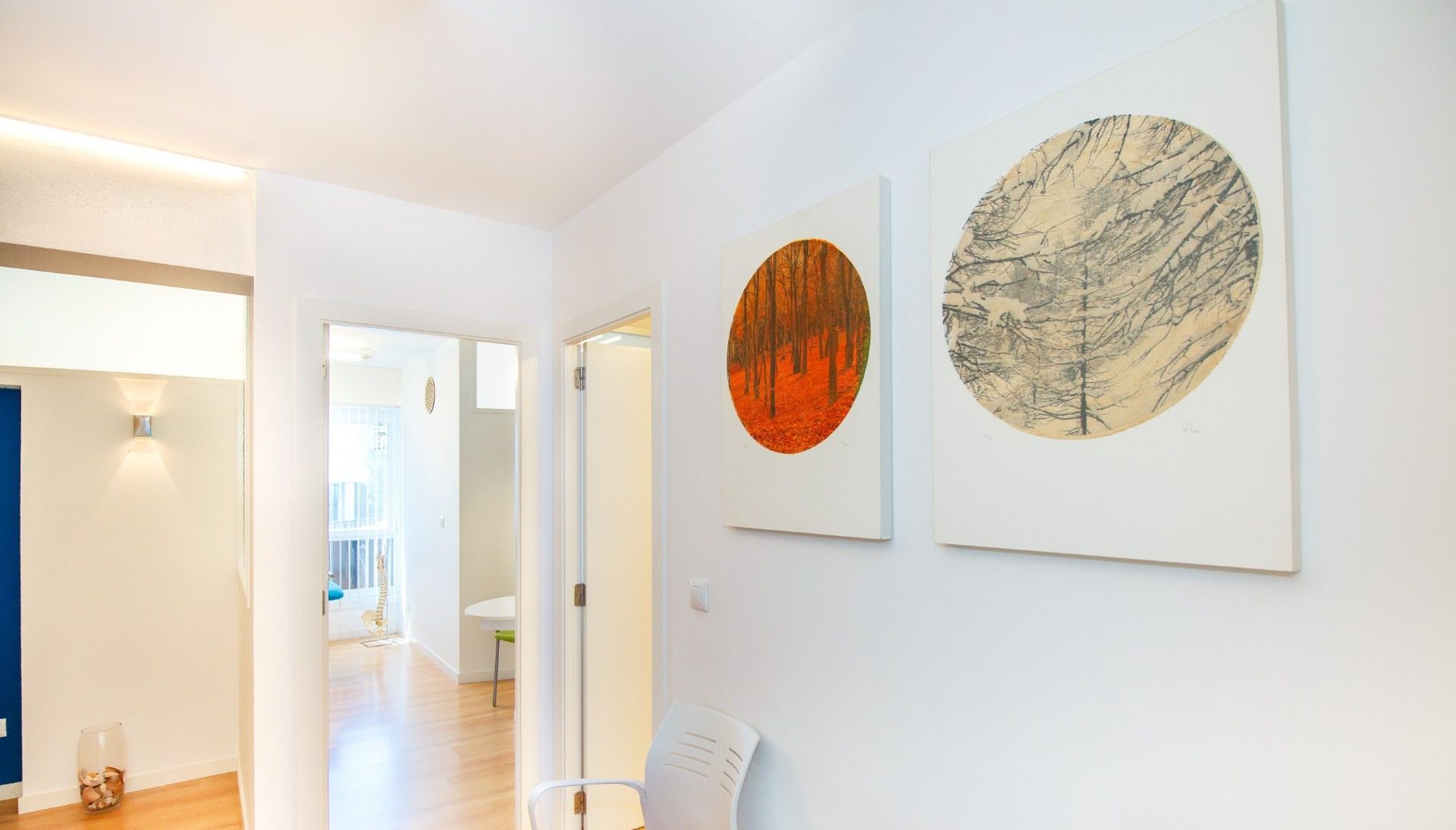 Habitación luminosa de color azul y blanco con dos camas individuales, estanterías y una pequeña zona de comedor al fondo.