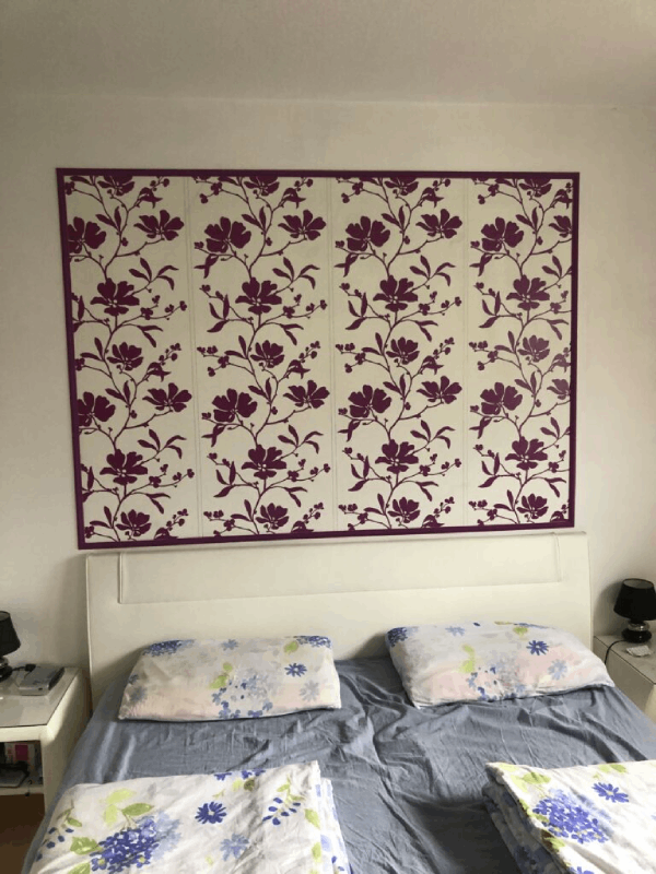 Ein Bett mit lila Blumen an der Wand dahinter