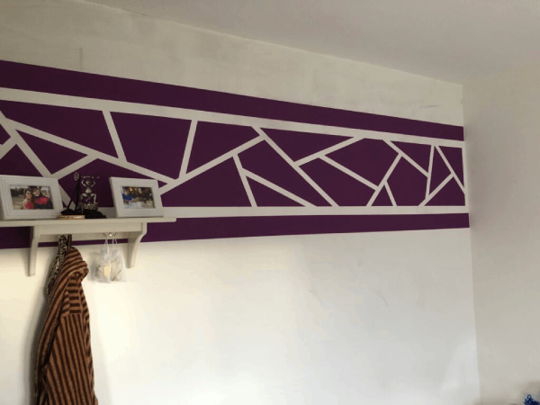 Eine weiße Wand mit einem violett-weißen geometrischen Muster darauf