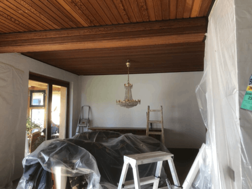 Ein Wohnzimmer mit Holzdecke und einem Kronleuchter, der von der Decke hängt.