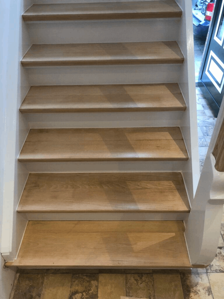 Eine Nahaufnahme einer Holztreppe mit weißen Stufen.