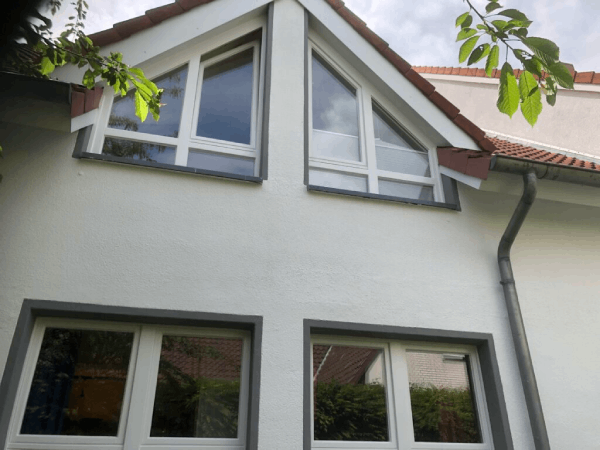 Ein weißes Haus mit rotem Dach und vielen Fenstern