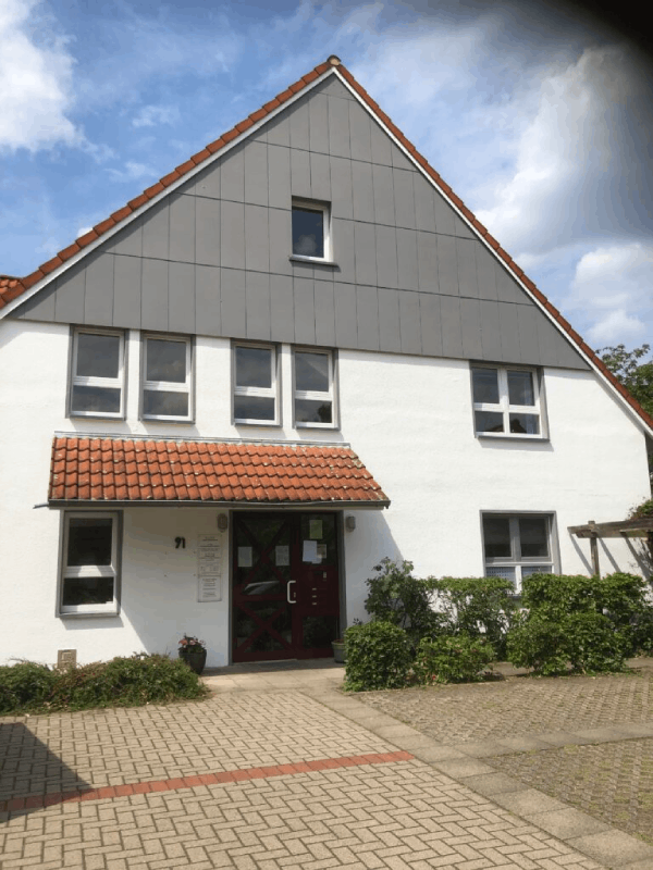 Ein weißes Haus mit einem grauen Dach und einer roten Tür