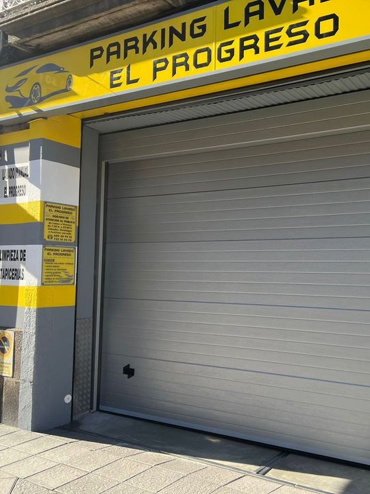 Un garaje con un cartel amarillo que dice parking lavado el progreso