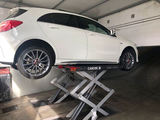 Un coche blanco está estacionado en un elevador en un garaje.
