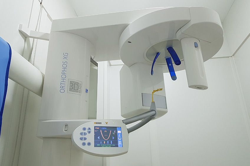 Una máquina de rayos X dental está colgada del techo de una habitación.