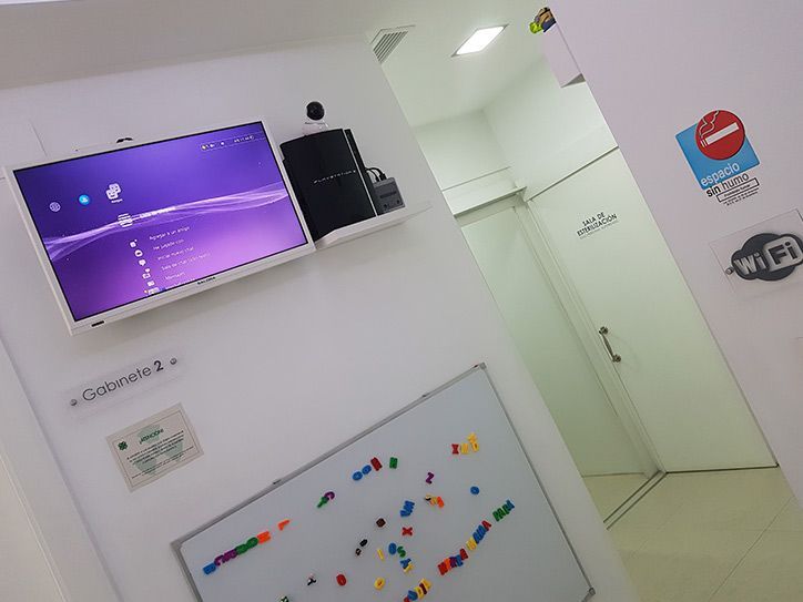 Una habitación con una pizarra y un televisor en la pared.