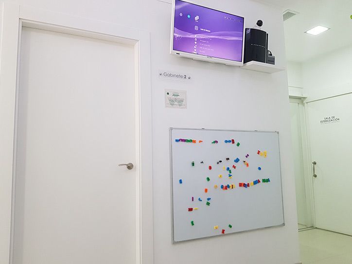 Una habitación con una pizarra y un televisor en la pared.