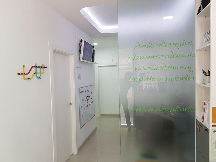 Un pasillo con una puerta de cristal y un televisor en la pared.