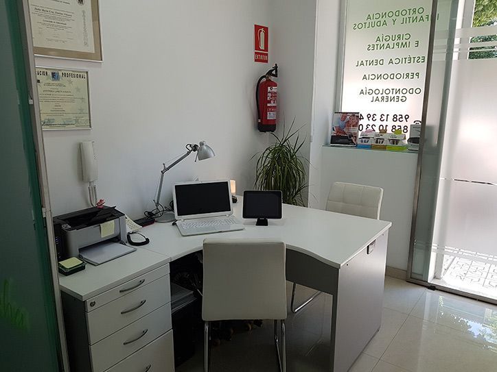 Un escritorio blanco con una computadora portátil encima en una habitación.