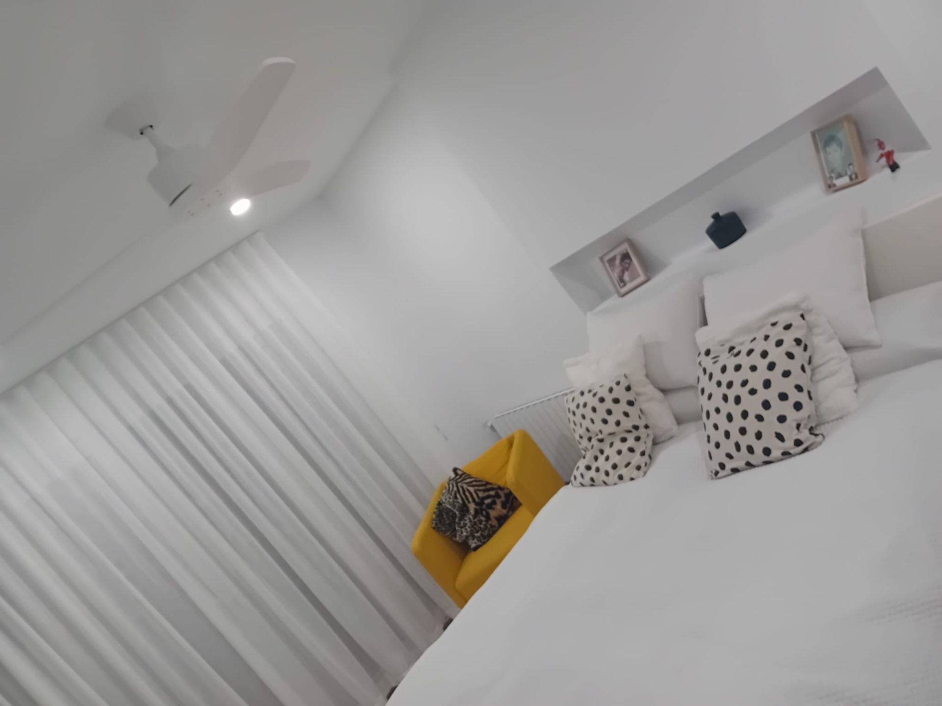 Baño con paredes de azulejos grises, ducha con marco negro, inodoro blanco y tocador de madera.