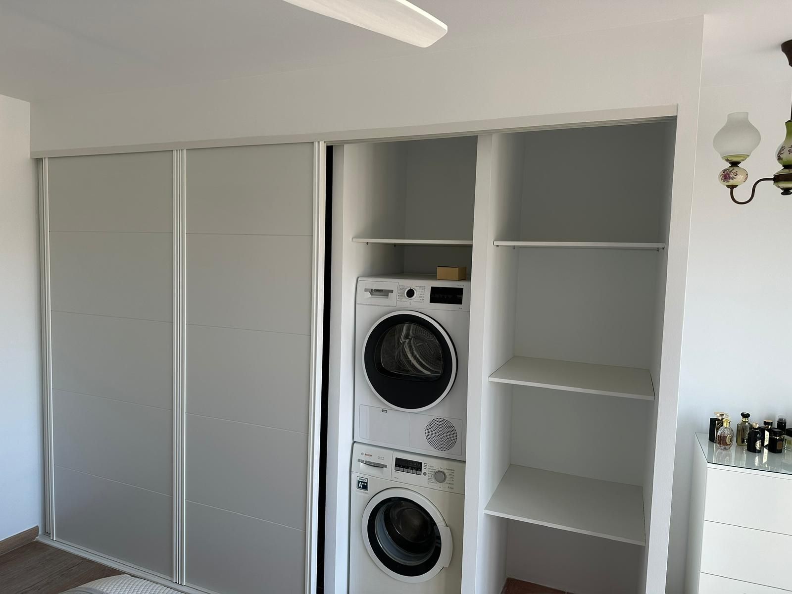 Cocina blanca con iluminación cenital, encimeras de madera, gabinetes y estufa a gas.