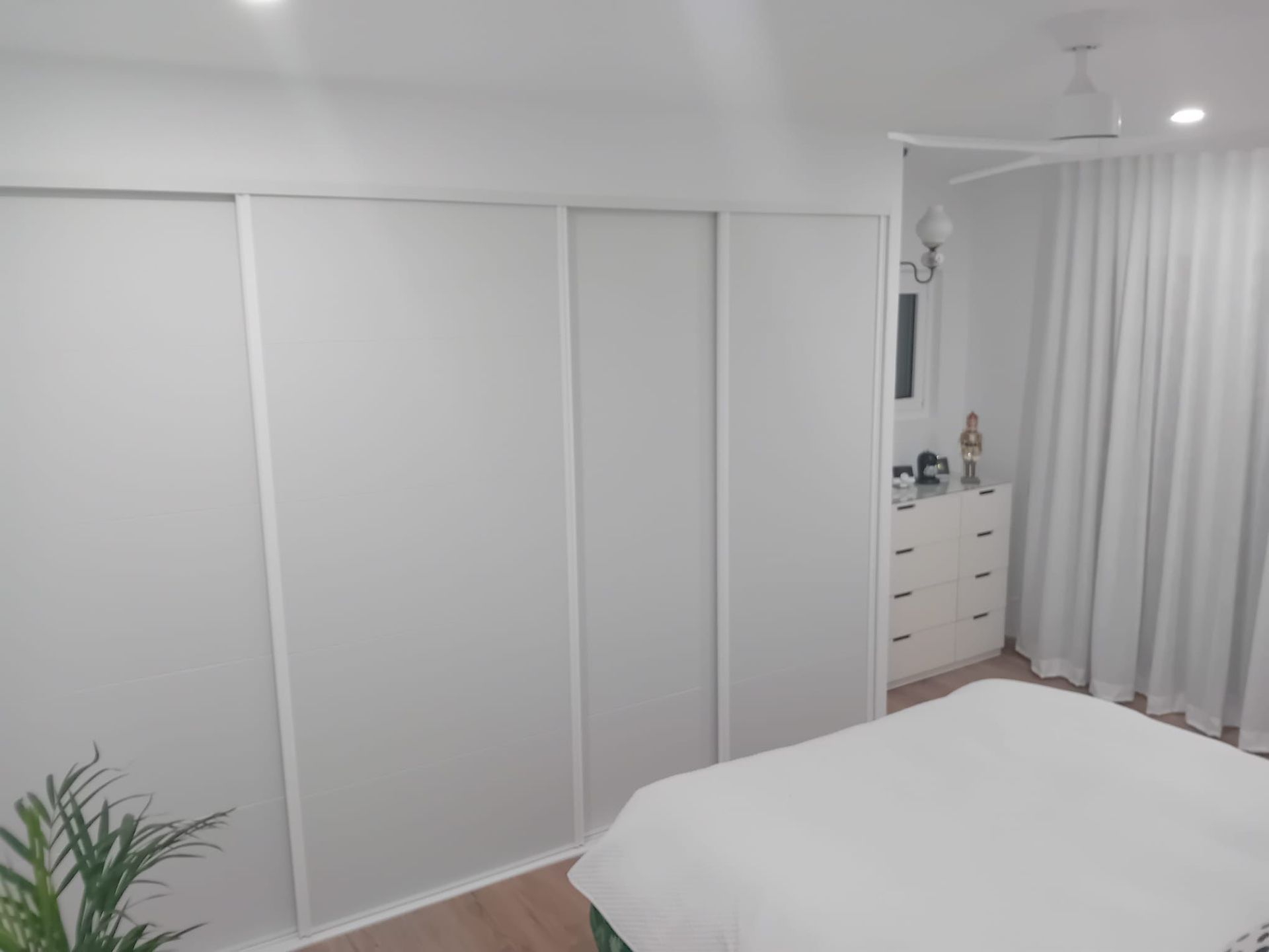 Cocina blanca con iluminación cenital, encimeras de madera, gabinetes y estufa a gas.