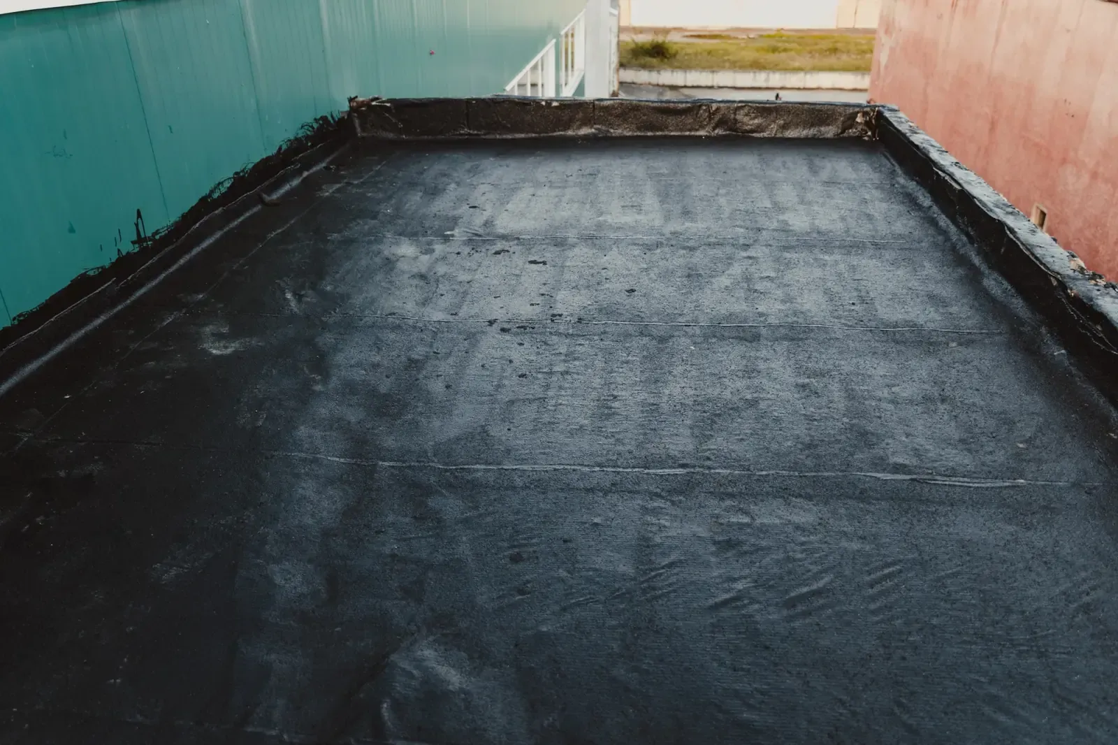 Techo plano de alquitrán negro con paredes bajas y laterales de construcción de color azul y rojo.