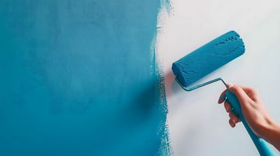 Peinture à la main d'un mur en bleu avec un rouleau ; peinture en cours.