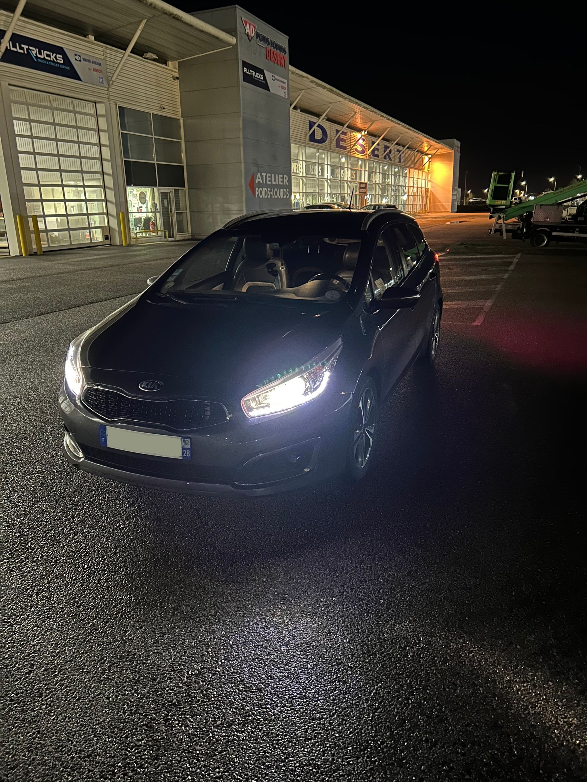 Vue d'une des voitures de l'entreprise dehors de nuit avec les phares allumés