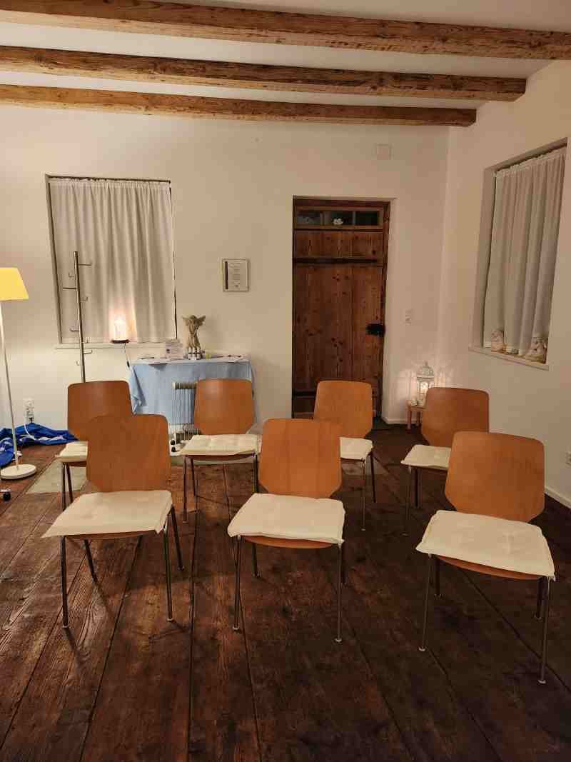 In einem Raum mit Holzboden steht eine Reihe von Stühlen.