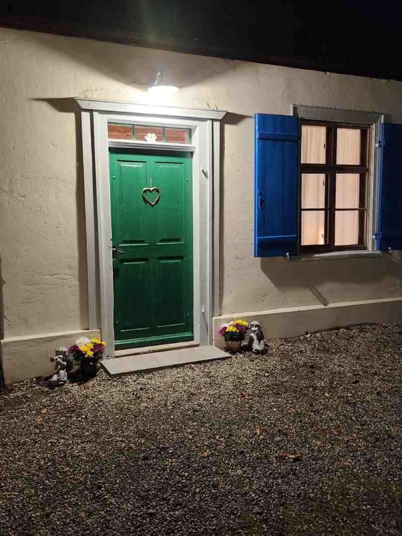 Ein Haus mit einer grünen Tür und blauen Fensterläden bei Nacht.