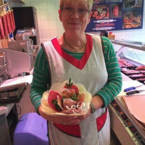 Eine Frau hält eine Schüssel mit Essen in einer Metzgerei