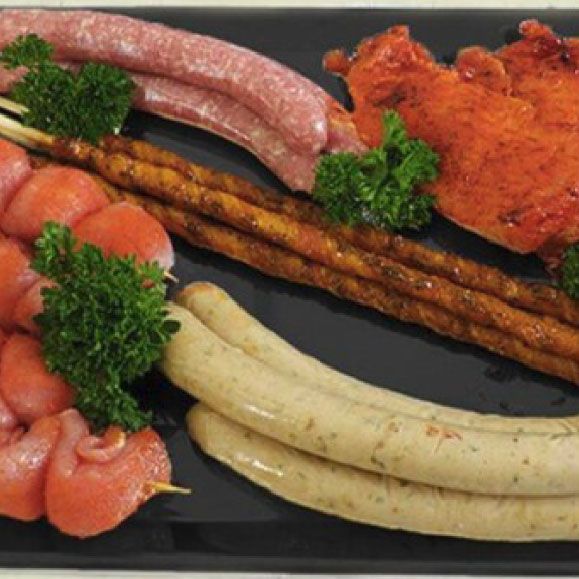 ein schwarzer Teller mit Hähnchenwürsten und Petersilie