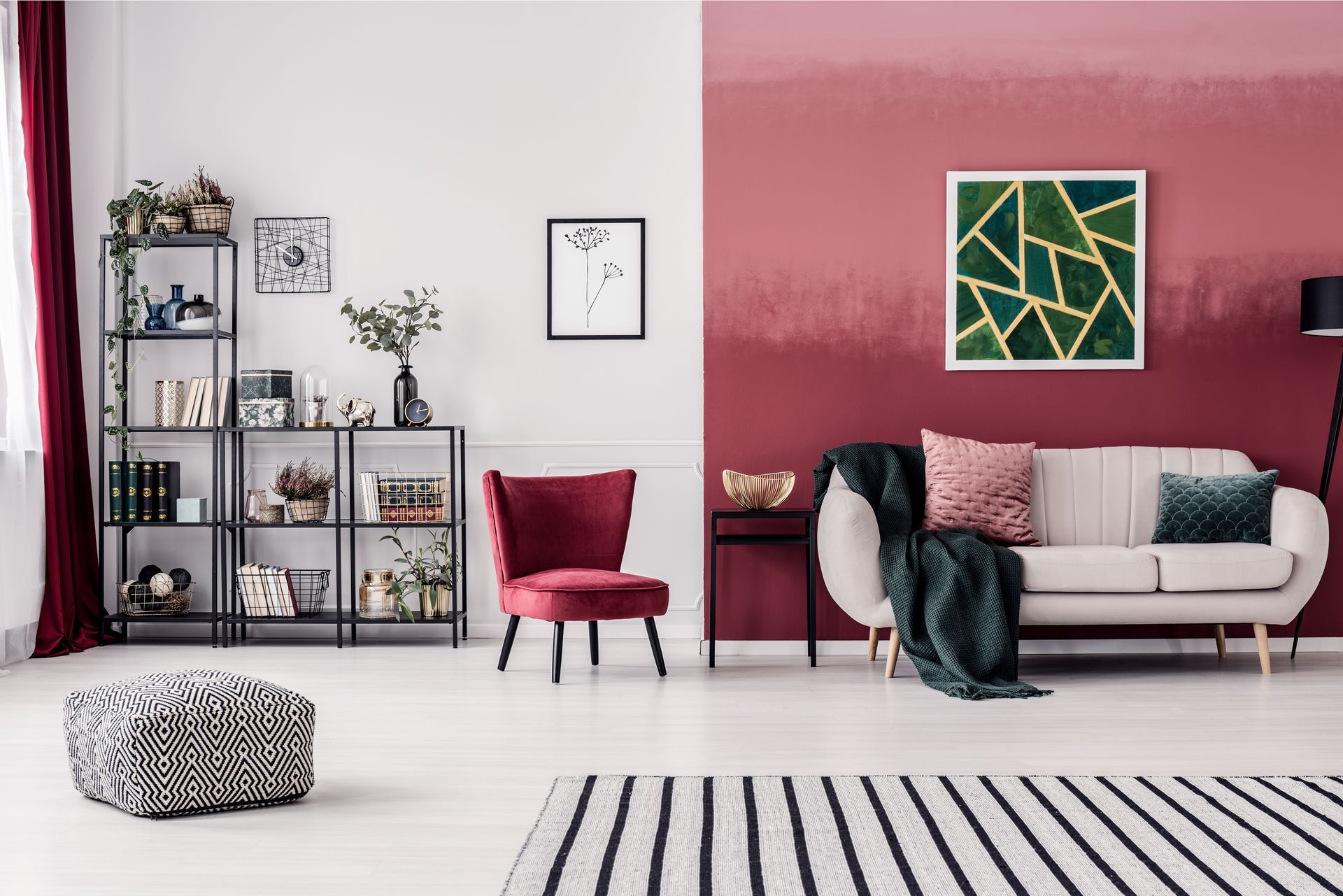 Salon moderne avec un mur d'accent rose, un canapé blanc, des étagères, un fauteuil rouge et un tapis à rayures noires et blanches