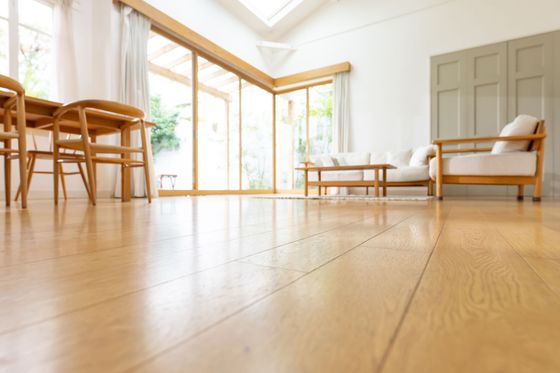 Salon lumineux avec parquet, grandes fenêtres, table à manger, chaises, canapé et table basse