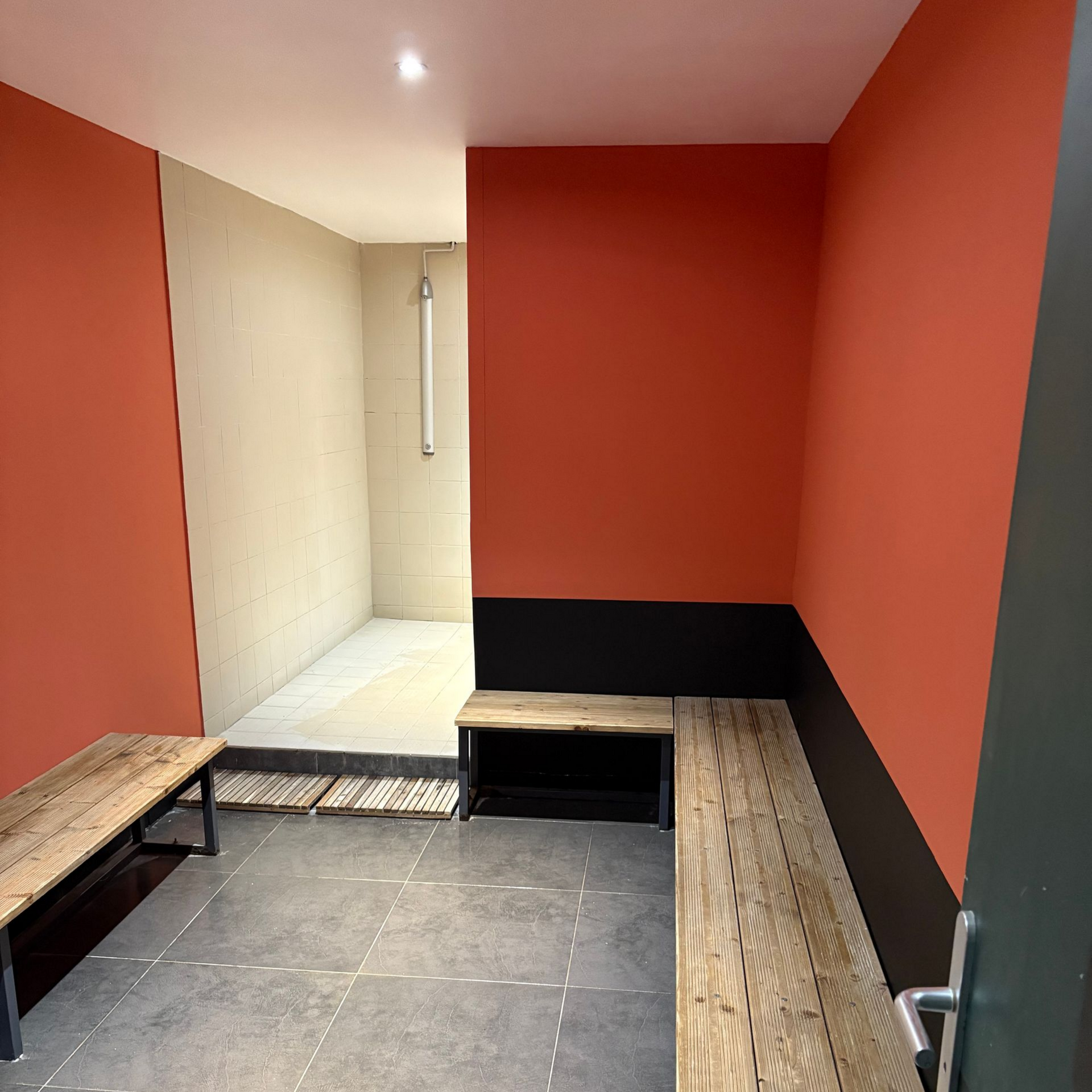 Pièce moderne vide avec murs orange, moulures noires, banquettes intégrées et sol carrelé.