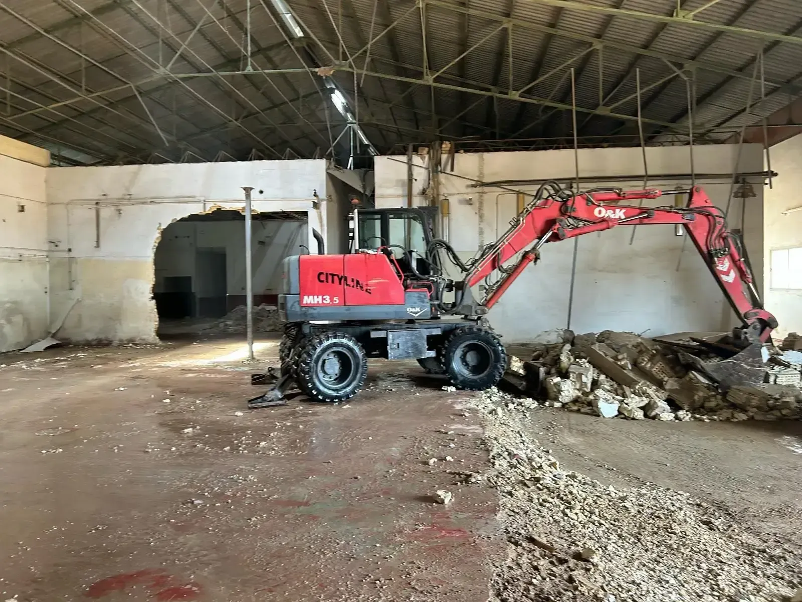 Una excavadora roja está dentro de un edificio vacío.