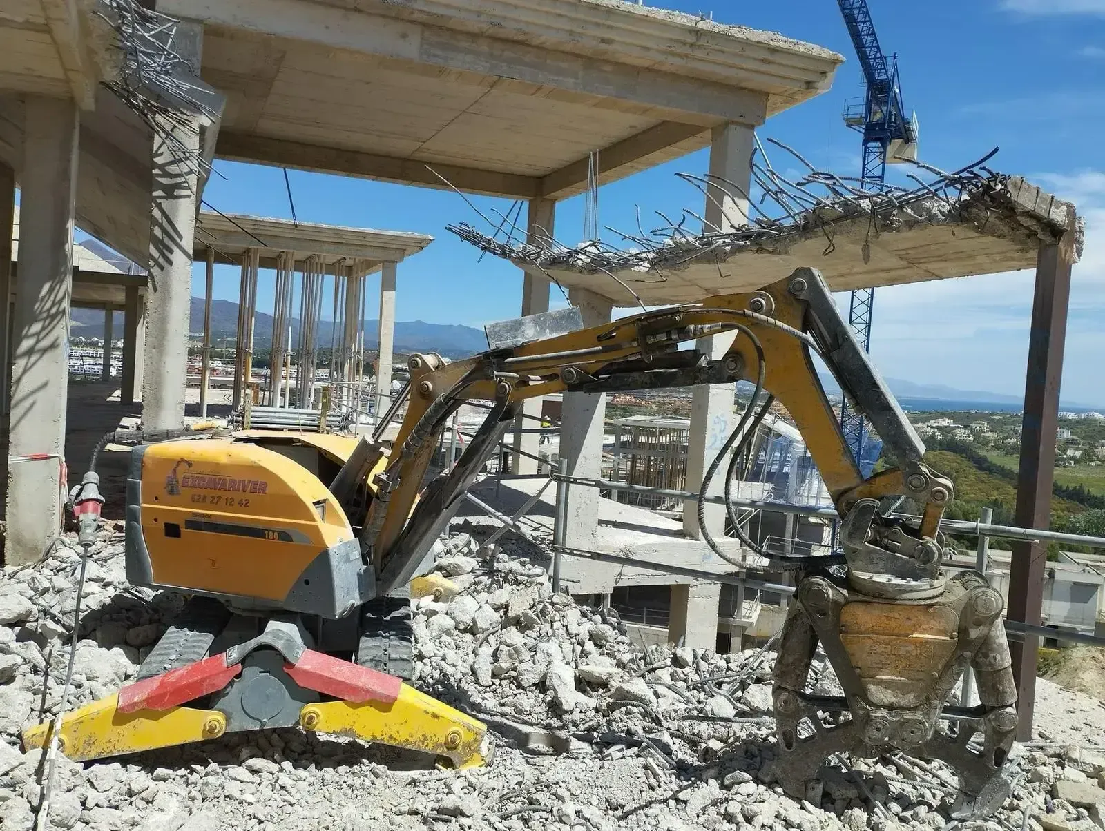 Una excavadora amarilla está trabajando en un edificio en construcción.