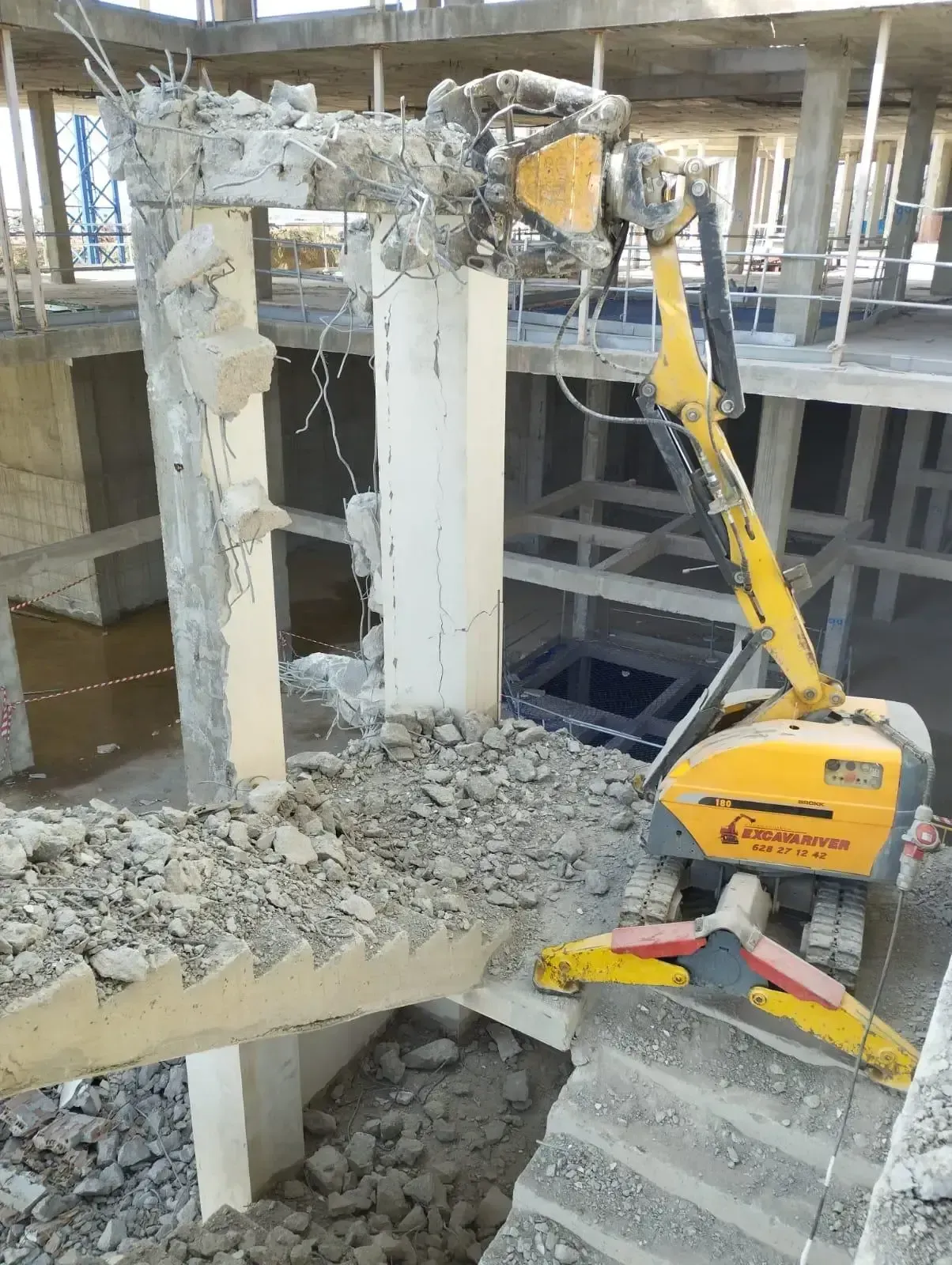 Una excavadora amarilla está demoliendo una estructura de hormigón.