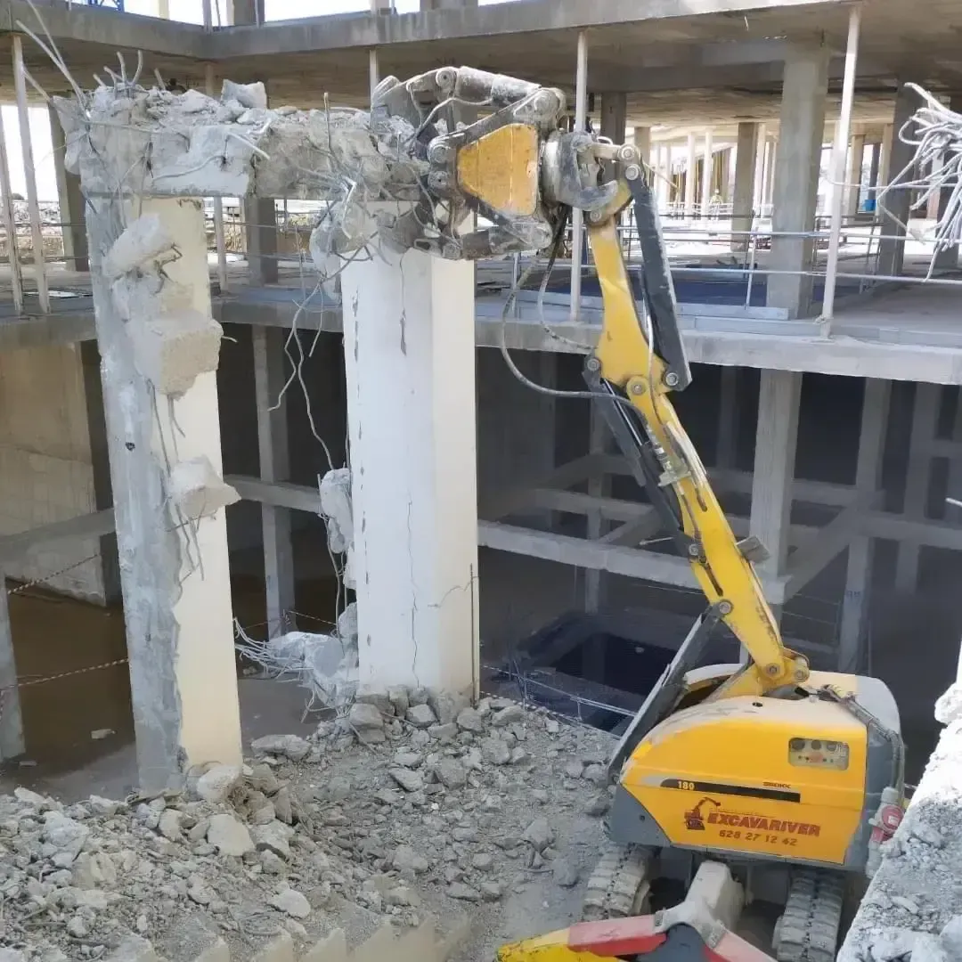 Se está utilizando una excavadora amarilla para demoler un edificio.