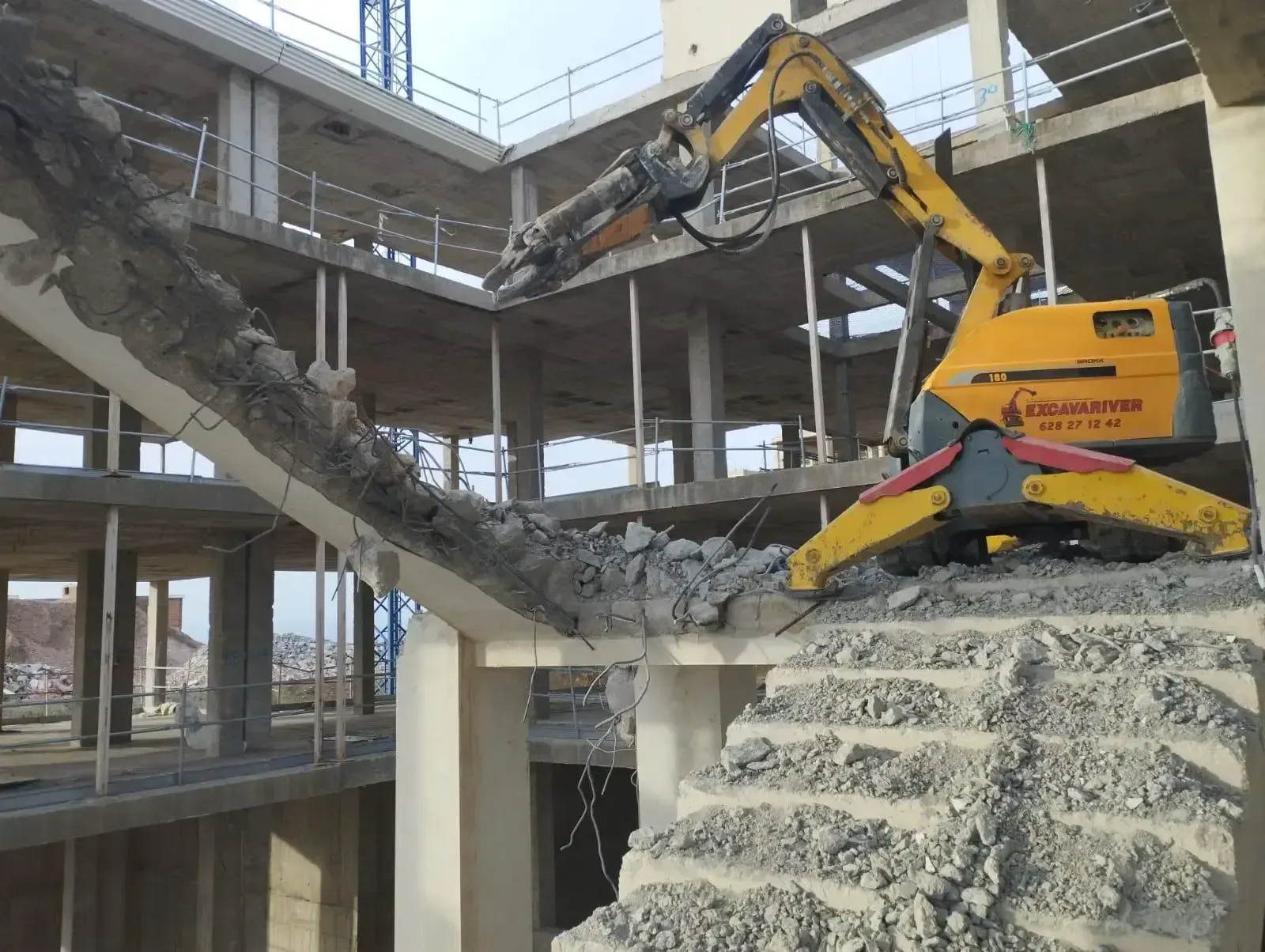 Una excavadora amarilla está demoliendo una escalera en un edificio en construcción.