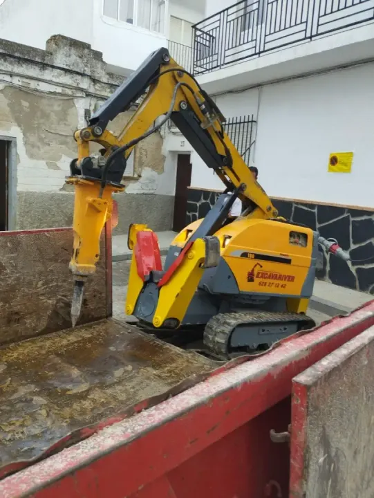 Una excavadora amarilla está sentada en un contenedor rojo.