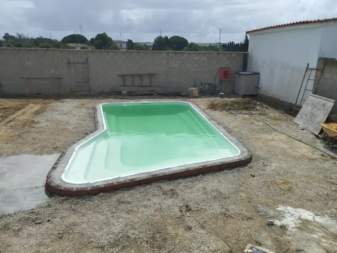 Se está construyendo una piscina verde en un patio trasero.