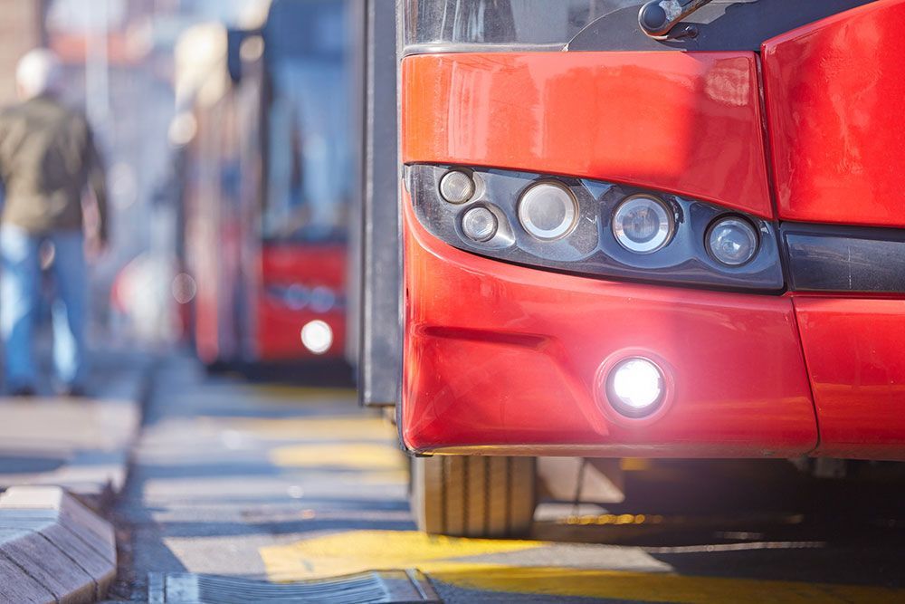 Rote Busfront mit leuchtenden Scheinwerfern, in einer Reihe geparkt.