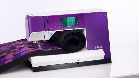 Una máquina de coser violeta está encima de una mesa blanca.