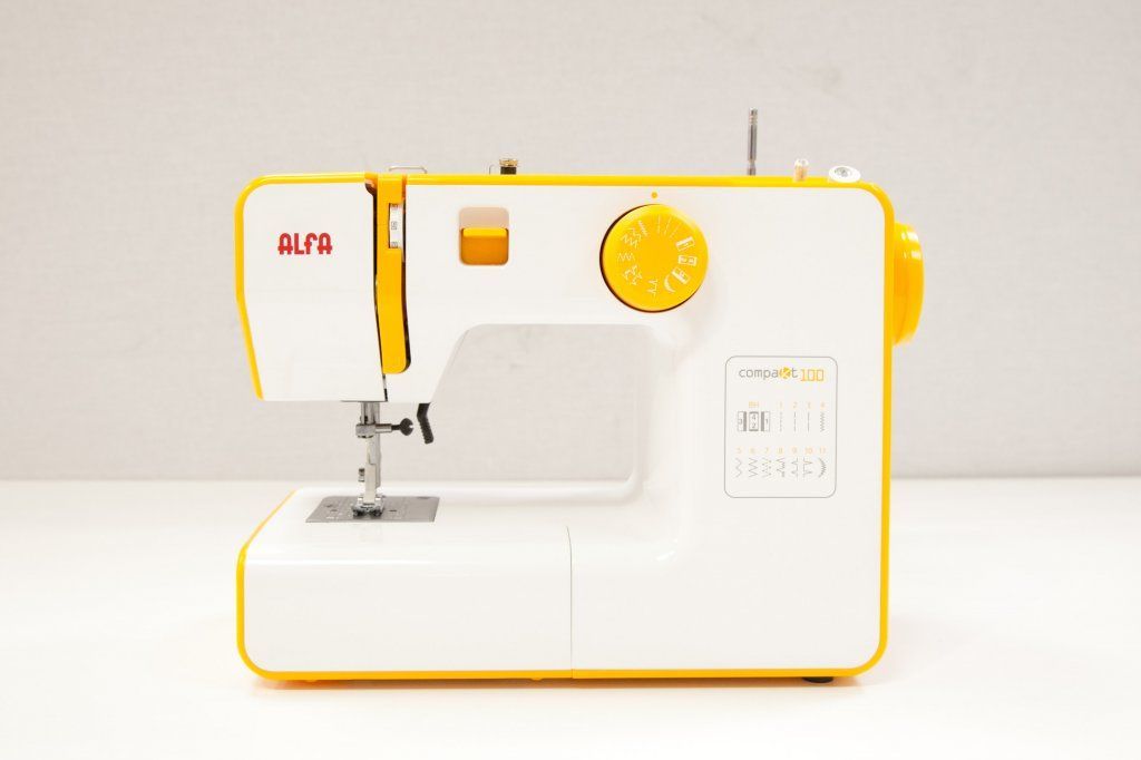 Una máquina de coser blanca y amarilla está sobre una mesa blanca.