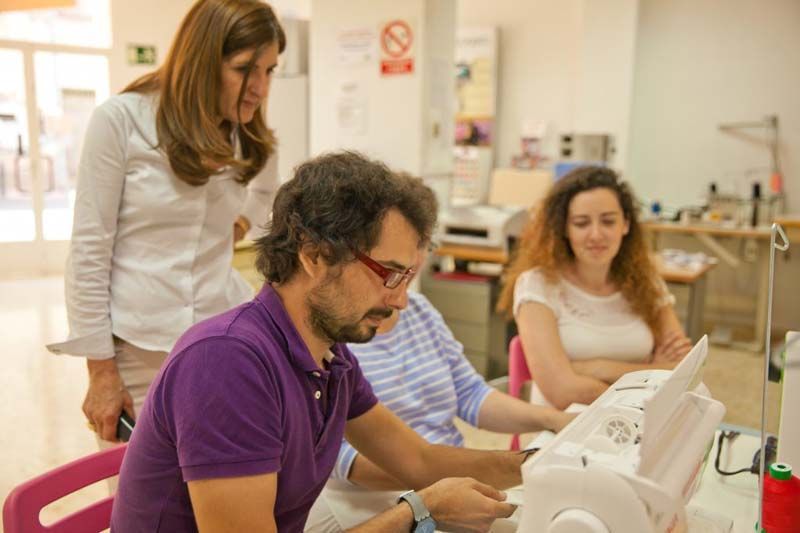 Un grupo de personas está sentada alrededor de una máquina de coser.
