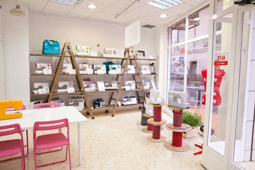 Una habitación con una mesa y sillas y un estante lleno de máquinas de coser.