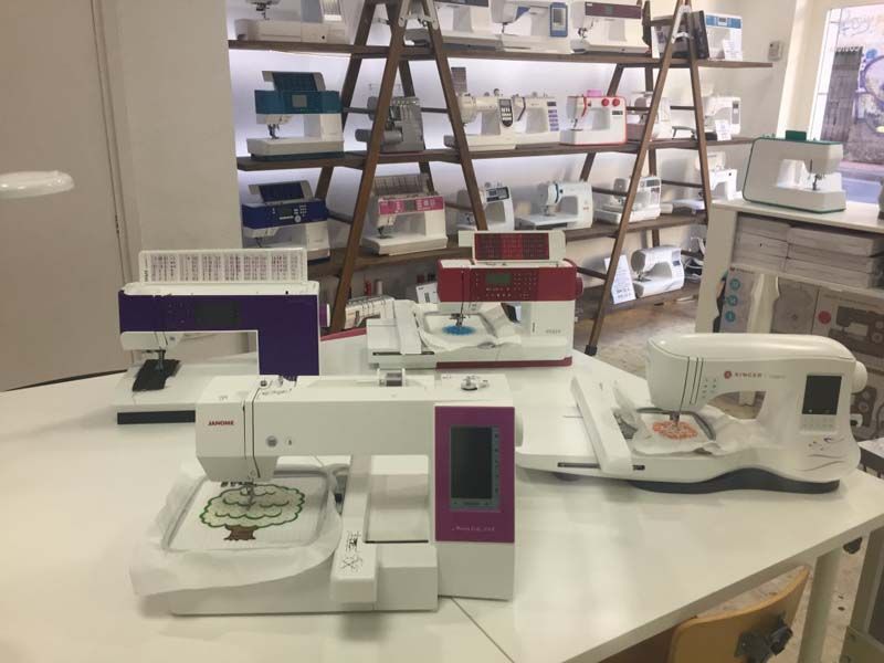 Tres máquinas de coser están sobre una mesa en una tienda.