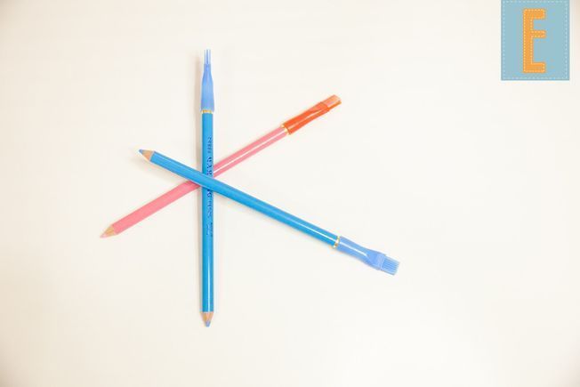Tres lápices y un bolígrafo sobre una superficie blanca con la letra f en la esquina
