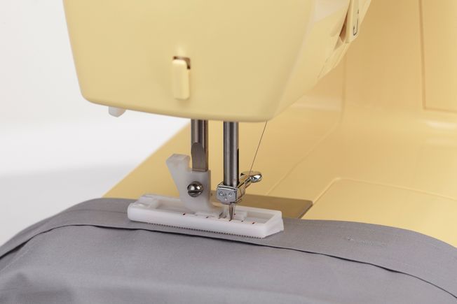 Una máquina de coser Singer amarilla sobre un fondo blanco